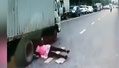 女子横穿马路摔入大货车底 险遭碾压